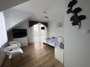 a white bedroom with a bed and a chair at Biebrzańska Dolina 1 in Goniadz