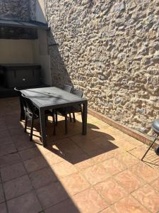 a wooden table and chairs in front of a stone wall at 3 pièces TERRASSE et JACUZZI in Nîmes