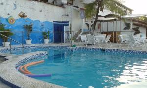 a swimming pool with chairs and a blue wall at Casas de Juan in Morro de São Paulo