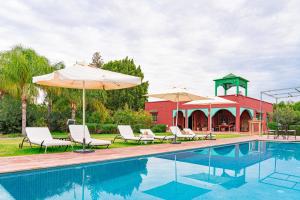 a pool with chairs and umbrellas next to a building at Bungalow with Pool View & Breakfast in Marrakesh