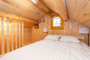 a bed in a wooden room with a window at The Little Cottage in Alleghe