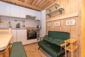 a living room with a green couch and a kitchen at The Little Cottage in Alleghe