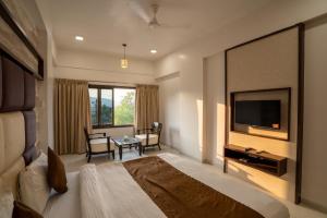 a hotel room with a bed and a television at Krushnai Resort in Kharakvasla