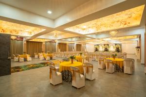 a banquet hall with yellow tables and white chairs at Krushnai Resort in Kharakvasla
