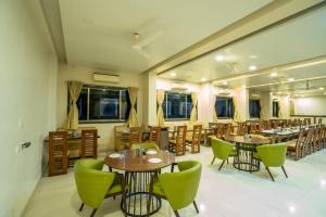 a restaurant with wooden tables and green chairs at Krushnai Resort in Kharakvasla