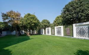 a green yard with white fences and trees at Krushnai Resort in Kharakvasla