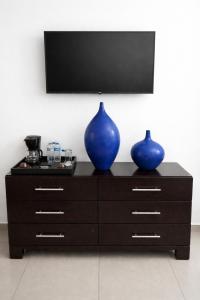 two blue vases sitting on a dresser with a television at Hotel Galerias HN in San Pedro Sula