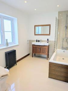 a bathroom with a tub and a sink and a mirror at Coastal Whisper Sleeps 10 with Parking in Reighton