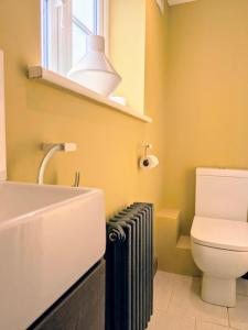 a bathroom with a sink and a toilet and a window at Coastal Whisper Sleeps 10 with Parking in Reighton