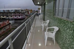 a row of white chairs sitting on a balcony at Frota Palace Hotel in Macapá