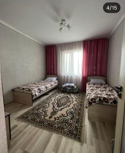 a bedroom with two beds and a rug at Коттедж in Cholpon-Ata
