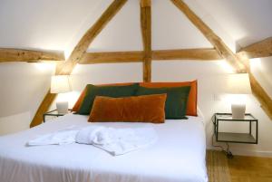 a bedroom with a white bed with green and orange pillows at La Roseraie in Barjouville
