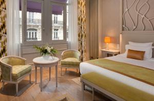 a hotel room with a bed and a table and chairs at Hôtel Château Frontenac in Paris +57 photos