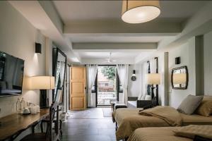 a bedroom with two beds and a living room at Palin Family Cottage in Chiang Rai