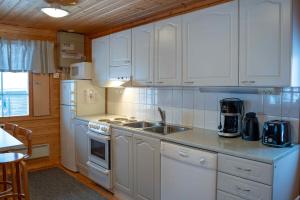 a kitchen with white cabinets and a sink and a stove at Syötekätkö in Syöte