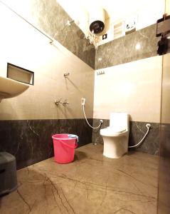 a bathroom with a toilet and a red bucket at Hotel ELITE Rameswaram in Rāmeswaram +15 photos