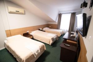 a hotel room with two beds and a flat screen tv at Zielony Dworek in Kraśnik