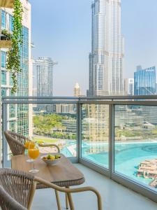 a balcony with a table and chairs and a view of the city at the 'New York' Condo - 4BR Executive Burj Khalifa Suite in Dubai