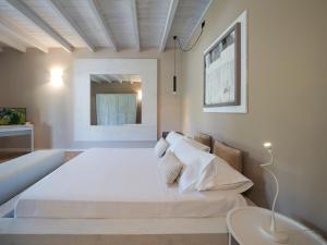 a bedroom with a large white bed and a table at Moscatello & Mulinër Design Agri Relais in Pozzolengo
