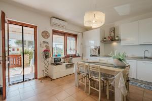 a kitchen with white cabinets and a table with chairs at villetta giulia fronte mare in Stintino