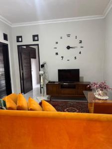 a living room with a couch and a clock on the wall at laksana homestay in Cireungit