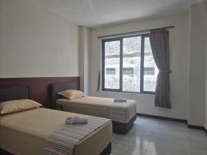 a hotel room with two beds and a window at ERCA Yogyakarta in Yogyakarta