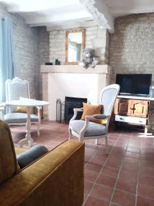 a living room with a couch and chairs and a fireplace at Au repos des elfes in Braye-sous-Faye