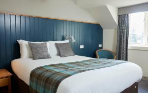 a bedroom with a large bed with a blue wall at St Leonards Hotel by Greene King Inns in Saint Leonards