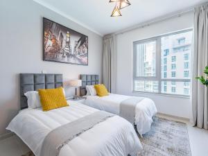 two beds in a white room with a window at the 'New York' Condo - 4BR Executive Burj Khalifa Suite in Dubai +57 photos