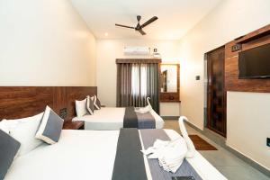 a hotel room with two beds and a flat screen tv at Hotel ELITE Rameswaram in Rāmeswaram