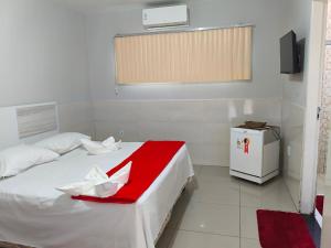 a bedroom with a bed with a red and white blanket at Hotel Senna in Arapiraca
