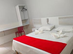 a bedroom with a white bed with a red blanket on it at Hotel Senna in Arapiraca