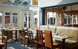 a restaurant with tables and chairs and windows at St Leonards Hotel by Greene King Inns in Saint Leonards