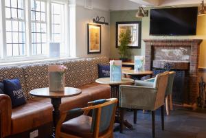 a restaurant with tables and a couch and a fireplace at St Leonards Hotel by Greene King Inns in Saint Leonards