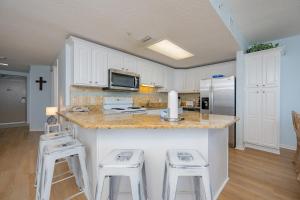 a kitchen with white cabinets and a counter with stools at Phoenix X 1110 in Orange Beach