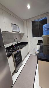 a small kitchen with a stove and a sink at Belo Apartamento Com Piscina in Várzea Grande