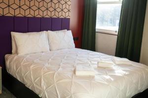 a large white bed with two towels on it at Roza Hotel in Enfield