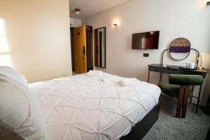 a bedroom with a bed and a desk with a computer at Roza Hotel in Enfield
