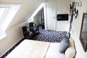 a bedroom with a bed and chairs and a television at Hotel Ribe in Ribe