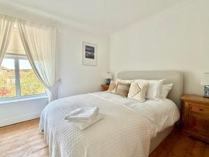 a white bedroom with a large bed and a window at Carrstone Cottage, Snettisham in Snettisham