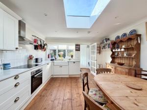 a kitchen with white cabinets and a wooden table at Carrstone Cottage, Snettisham in Snettisham