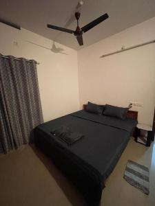 a bedroom with a black bed with a ceiling fan at Southern Cliff House in Varkala