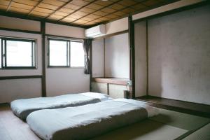 two beds in a room with two windows at サカナギゲストハウス in Nagano