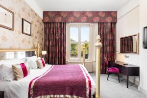 a bedroom with a bed and a desk and a window at Coulsdon Manor Hotel and Golf Club in Croydon +87 photos