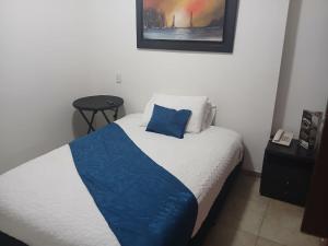 a bedroom with a bed with a blue blanket on it at Hotel estación Kristal - Corferias in Bogotá