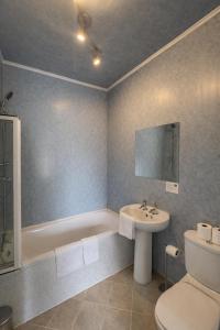 a bathroom with a toilet and a sink and a tub at The Anchorage in Troon