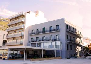a white building with balconies on the side of it at Plaza Hotel in Loutraki