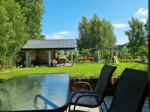 a backyard with a pool with chairs and a swing at Slow Łeba Relaksowa - Apartamenty z aneksami kuchennymi in Łeba