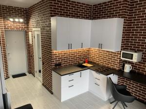 a kitchen with white cabinets and a brick wall at Стильна смарт-квартира in Odesa +4 photos