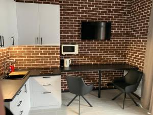 a kitchen with white cabinets and a brick wall at Стильна смарт-квартира in Odesa